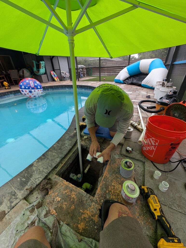 Gluing new PVC fittings during an underground pool plumbing repair through a small deck opening