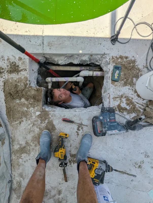 Splash technician accessing underground pool plumbing during a leak detection and repair job